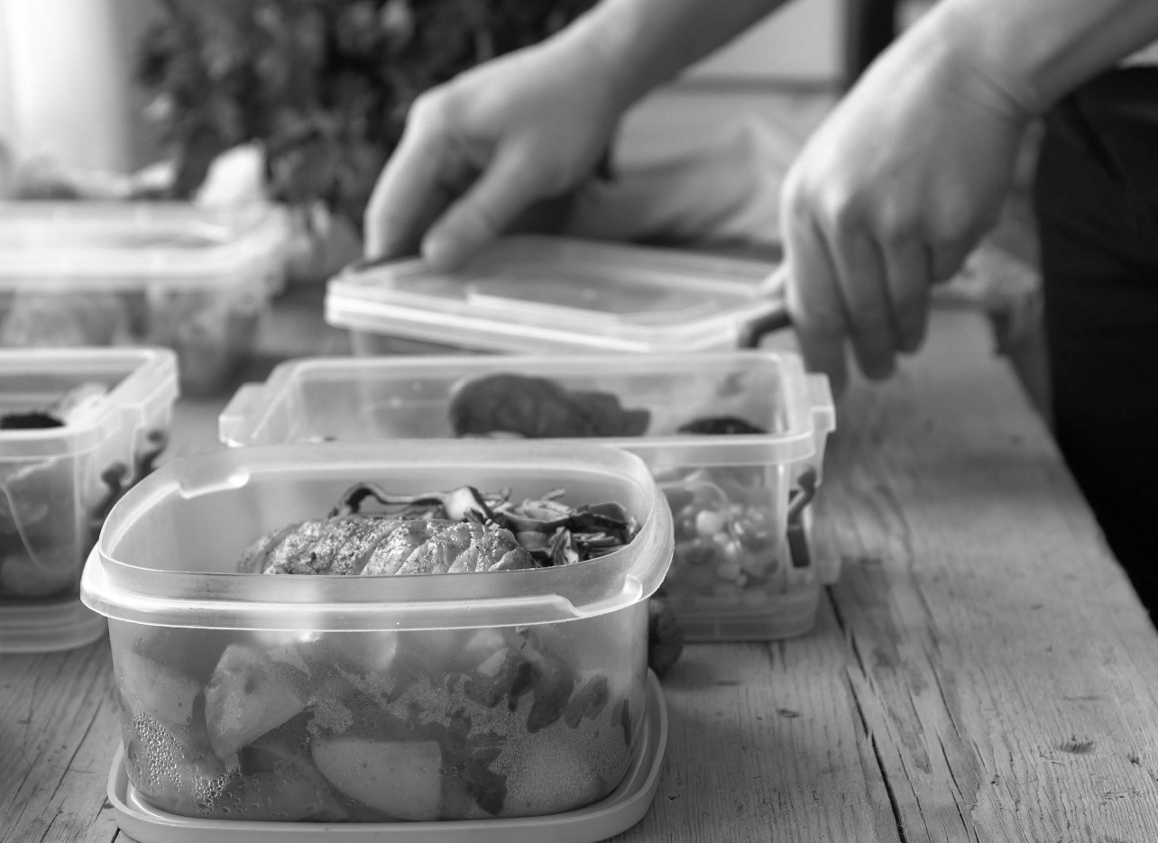 a person portioning meals into plastic containers
